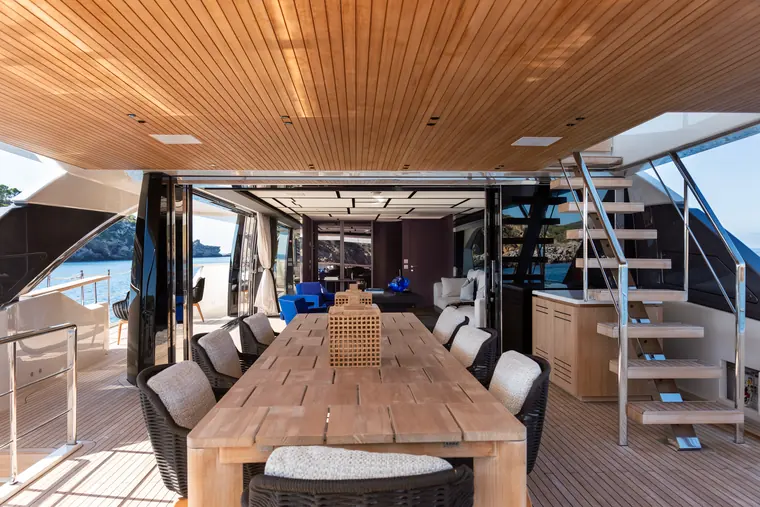 Long dining table under a teak ceiling, open to the sea
