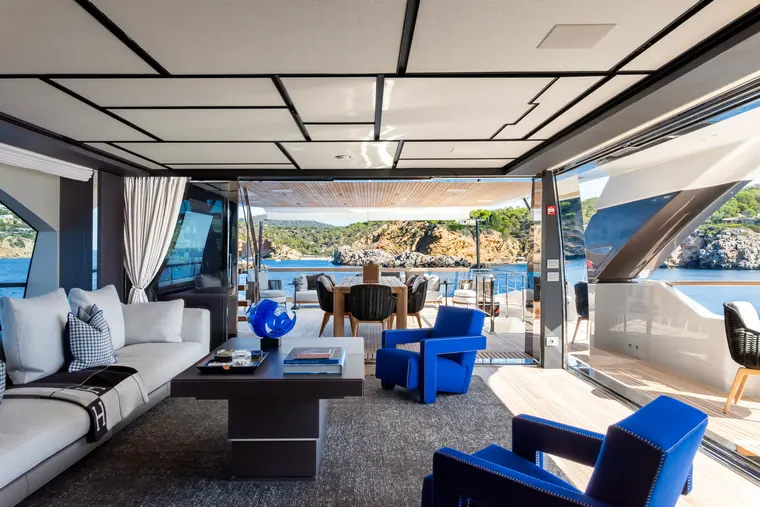 Upper deck lounge with blue armchairs, the dining table behind