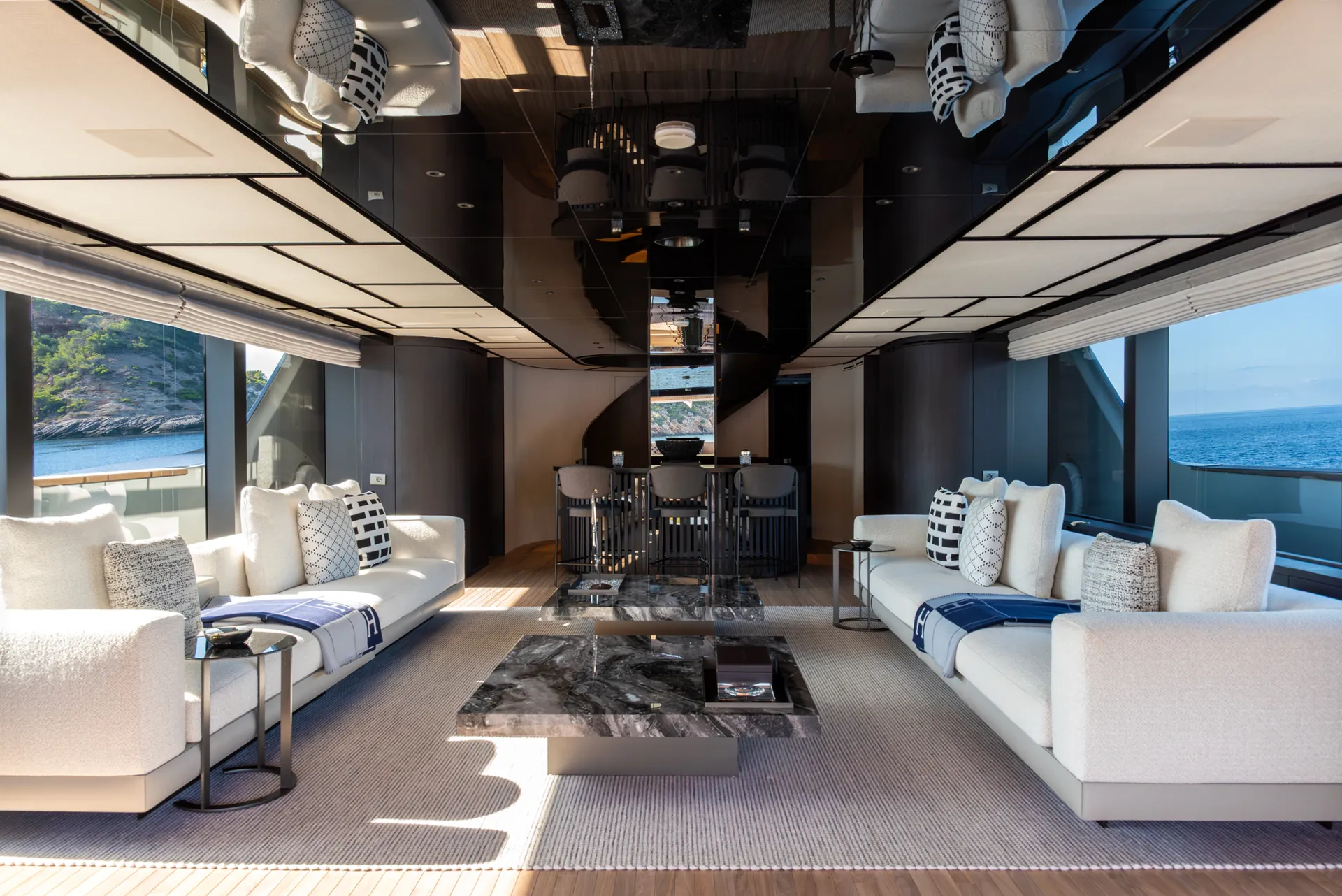 Main salon with two white sofas, a stone table and windows on both sides